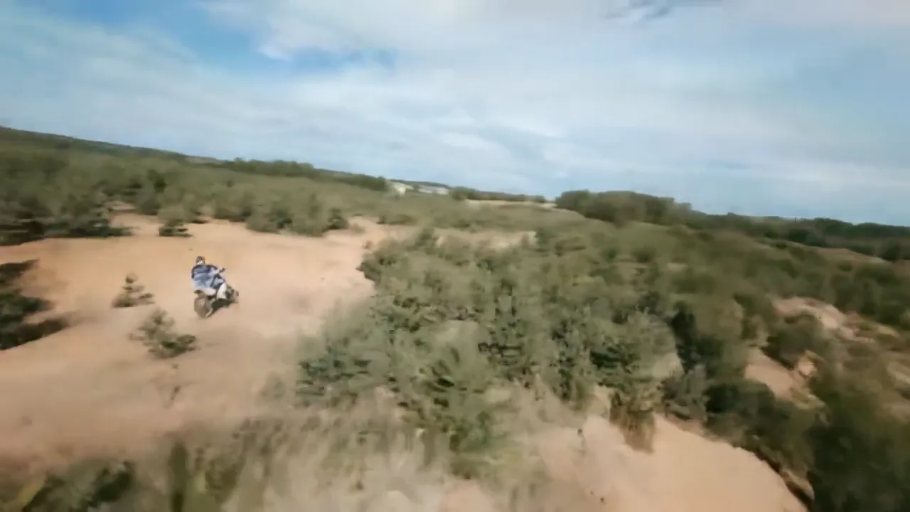 A dirt bike rider cresting a blind rise on an off-road trail, with no view of what is on the other side.